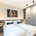 Schlafzimmer mit Doppelbett, Kleiderschrank und Wandbild eines Löwen.