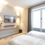 Schlafzimmer mit Doppelbett, Fenster und Wandbild.