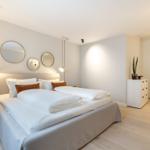 Schlafzimmer mit Doppelbett, drei runden Spiegeln und Kleiderschrank.