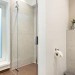 Badezimmer mit Dusche, Toilette und Pflanzen an Fensterbank.