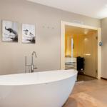 Bad mit freistehender Badewanne und Blick in die Sauna.