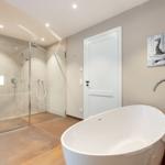 Bad mit freistehender Badewanne und Dusche mit Glaswand