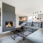 Wohnzimmer mit Kamin, Sofa und Esstisch. Moderne Einrichtung mit schwarzen Lampen.