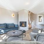 Living room with sofa, fireplace, and dining area in background.
