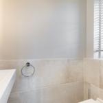 Bathroom with sink, towel ring, and window with blinds.