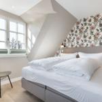 Bedroom with bed, chair, and window. Wall with floral pattern.