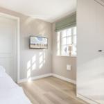 Bedroom with bed, TV, and window with green roller blind.