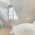 Bathroom with sloped ceilings, window, sink, and toilet.