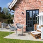 Red brick building with terrace, table, chairs, and beach chair.