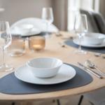 Round table set with dinnerware and glasses for four people.