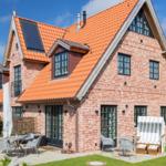 Red tile roof, brick house with patio and garden furniture.