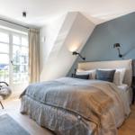 Bedroom with sloped ceiling, bed, window, and chair.
