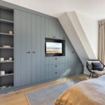 Bedroom with gray closet, TV, and window with view.