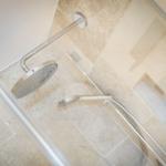 Shower area with handheld shower and showerhead mounted on wall and floor