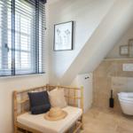 Shower with bamboo bench, window and stone tiles