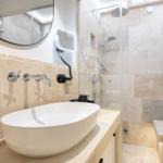 Bathroom with shower, sink, and mirror on stone wall