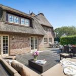 House with thatched roof and terrace with seating and table.
