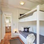 Bedroom with bunk bed, window, and view into the bathroom.