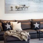 Gray sofa with pillows and blanket under wall art with sheep.