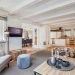 Living and dining area with kitchen. Visible beams, fireplace, and TV.