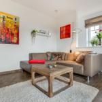 Wohnzimmer mit Ledersofa, Holztisch und Wandbildern.