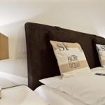 Schlafzimmer mit Bett, Kissen und Nachttisch mit Lampe.