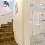 Treppenhaus mit Holztreppe und angrenzender Dusche mit Glaswand.