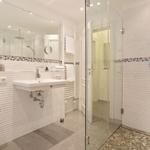 Badezimmer mit Dusche, Waschbecken und Spiegel.