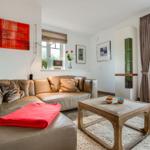 Ein Wohnzimmer mit braunem Ledersofa, Holztisch und Fensterblick.