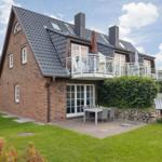 House with balcony, terrace, and garden. Modern design with red brick and dark roof.