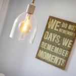 Hanging lamp with glass shade and wall plaque with text.