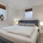 Bedroom with double bed, two windows, and nightstands.