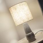 Table lamp with fabric shade on round table beside seating furniture.
