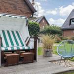 Green and white beach chair on terrace with blue rattan chair.