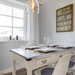 Dining area with table, chairs, and window. Wall art and pendant lamp.