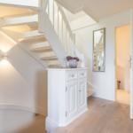 Hallway with stairs, cabinet, and door to the bathroom.