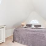 Bedroom with sloped ceiling, large bed, and window.