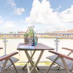 Balcony with table, two chairs, and a basket with flowers.