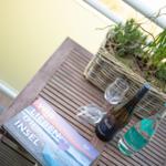 Table with wine, water, and flowers on balcony.