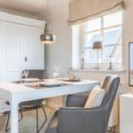Dining area with table, chairs, and TV. Window with view of roof and tower.