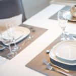 Table set for two, with plates, glasses, and cutlery.