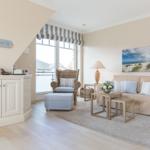 Wohnzimmer mit Sofa, Sessel und Fenster zur Aussicht