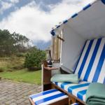 Blue-and-white beach chair with drink and green towels in the garden
