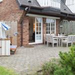 Backyard with patio, table, chairs, and beach cabana. Wooden fence and brick house.