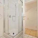 Bathroom with shower, washing machine, and sink. Door leads to living area.