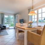 Dining room with table and chairs, living area with sofa and window front.