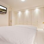 Bedroom with double bed, white wardrobes, and wall-mounted TV.