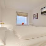 Bedroom with bed, window, and wall-mounted TV.