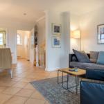 Living and dining area with sofa, table and chairs on tile floor.