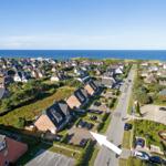 Aerial view of coastal village with houses and ocean in background.